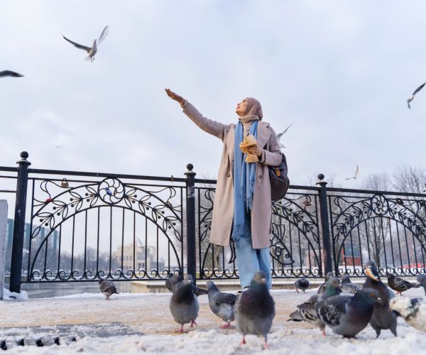 muslim-woman-feeding-pigeons-while-traveling-city